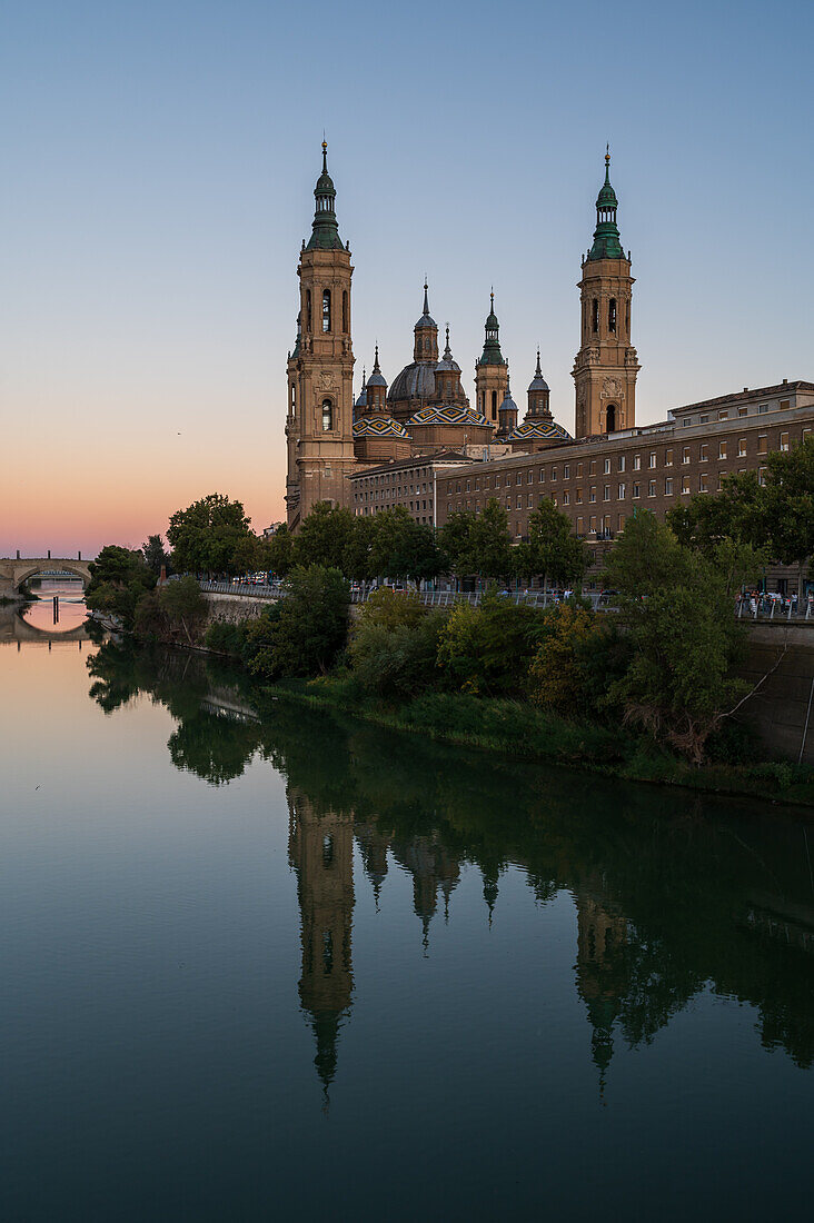 Cathedral-Basilica of Our Lady of the Pillar reflected on the Ebro River at sunset, Zaragoza, Spain