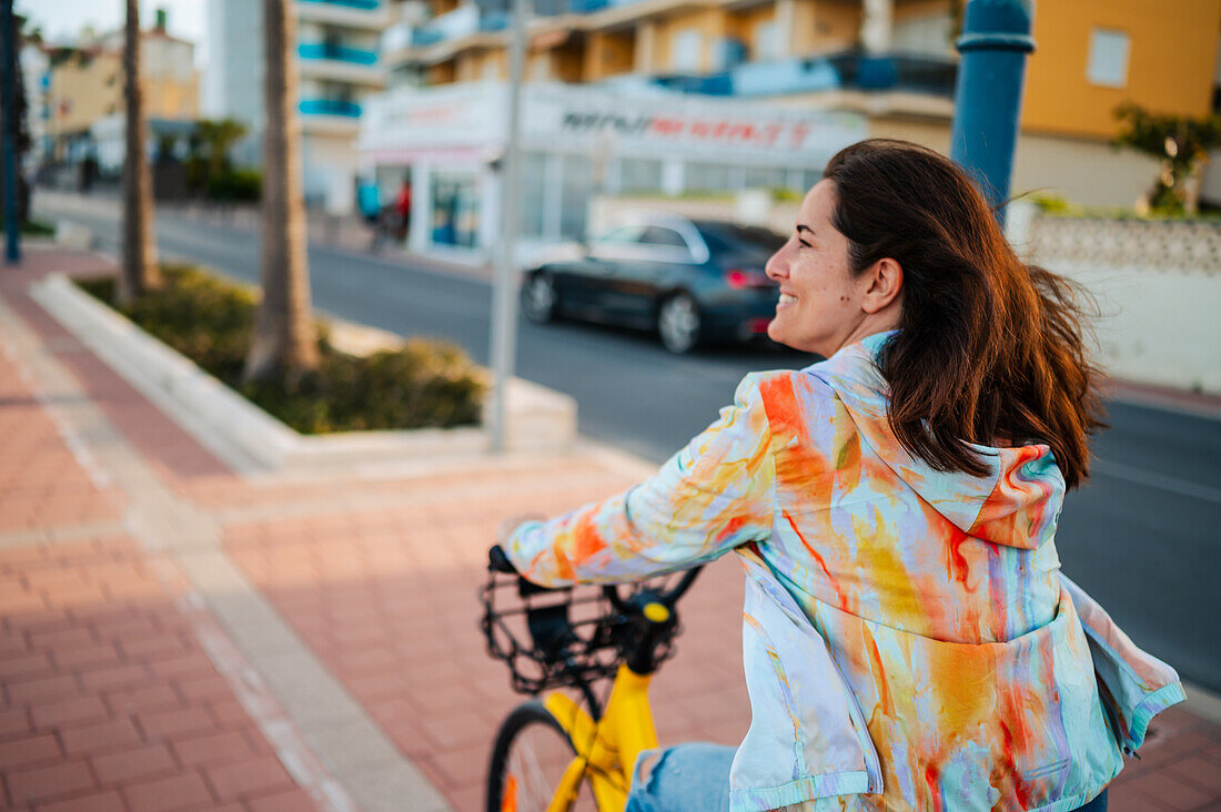 Frau fährt mit dem Fahrrad an der Promenade entlang, Peñiscola, Spanien