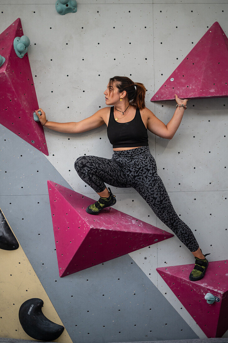 Young man in her twenties climbing on a climbing wall indoors