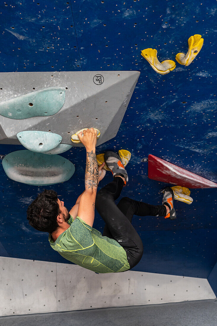 Young man in his twenties climbing on a climbing wall indoors