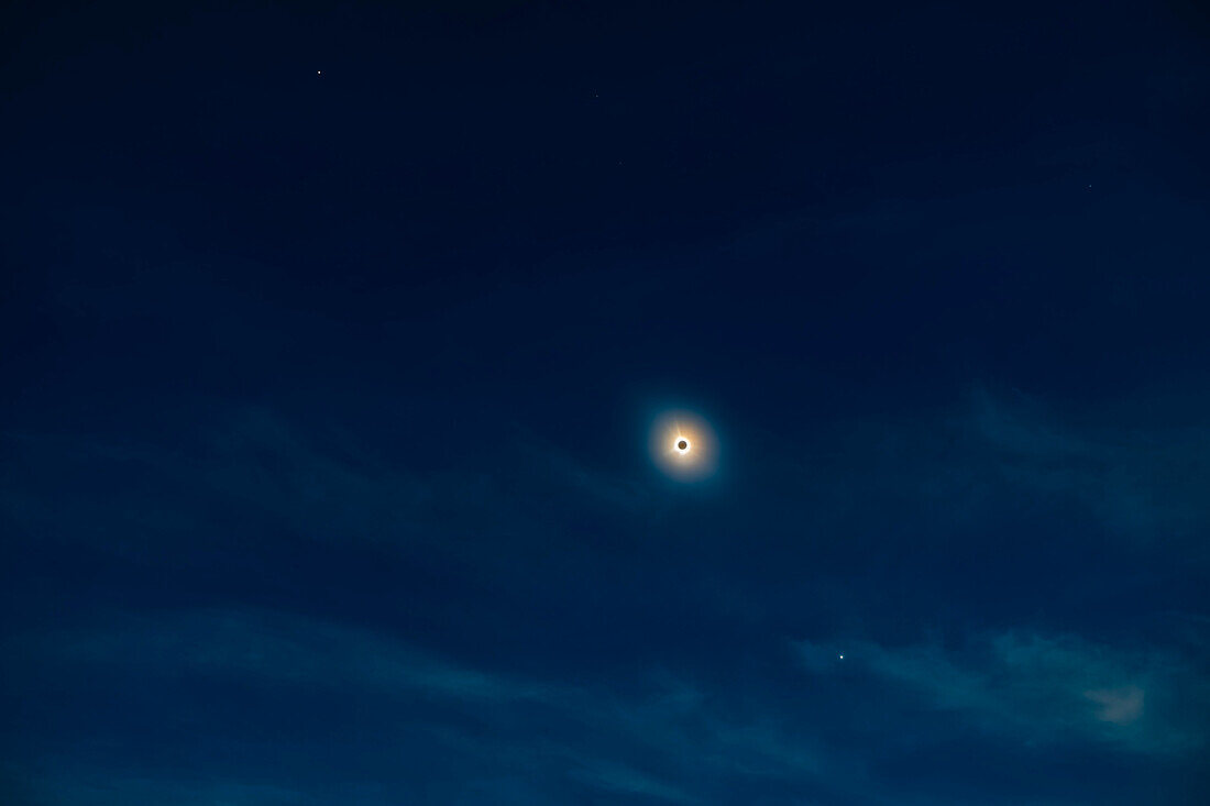 This is a wide-field view of the April 8, 2024 total eclipse of the Sun, taking in the bright planets Jupiter (at top) and Venus (below) that were easily visible to the unaided eye during totality. Here the Sun appears only as its outer atmosphere, the corona, in shades of yellow and blue, surrounding the dark disk of the Moon.