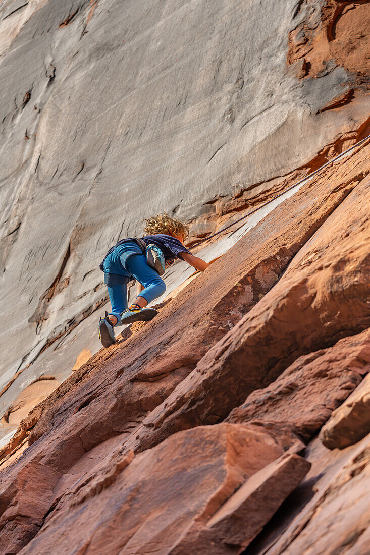 Ein 6-jähriger Junge lernt im Hunter Canyon in der Nähe von Moab, Utah, das Klettern.