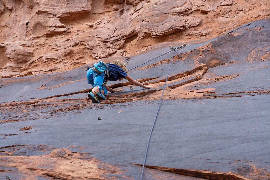 Ein 6-jähriger Junge lernt im Hunter Canyon in der Nähe von Moab, Utah, das Klettern.