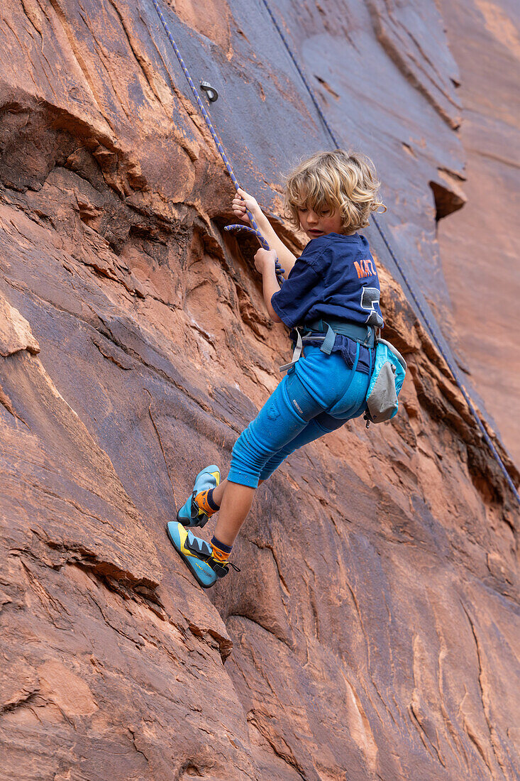 Ein 6-jähriger Junge seilt sich ab, während er im Hunter Canyon bei Moab, Utah, das Klettern lernt.