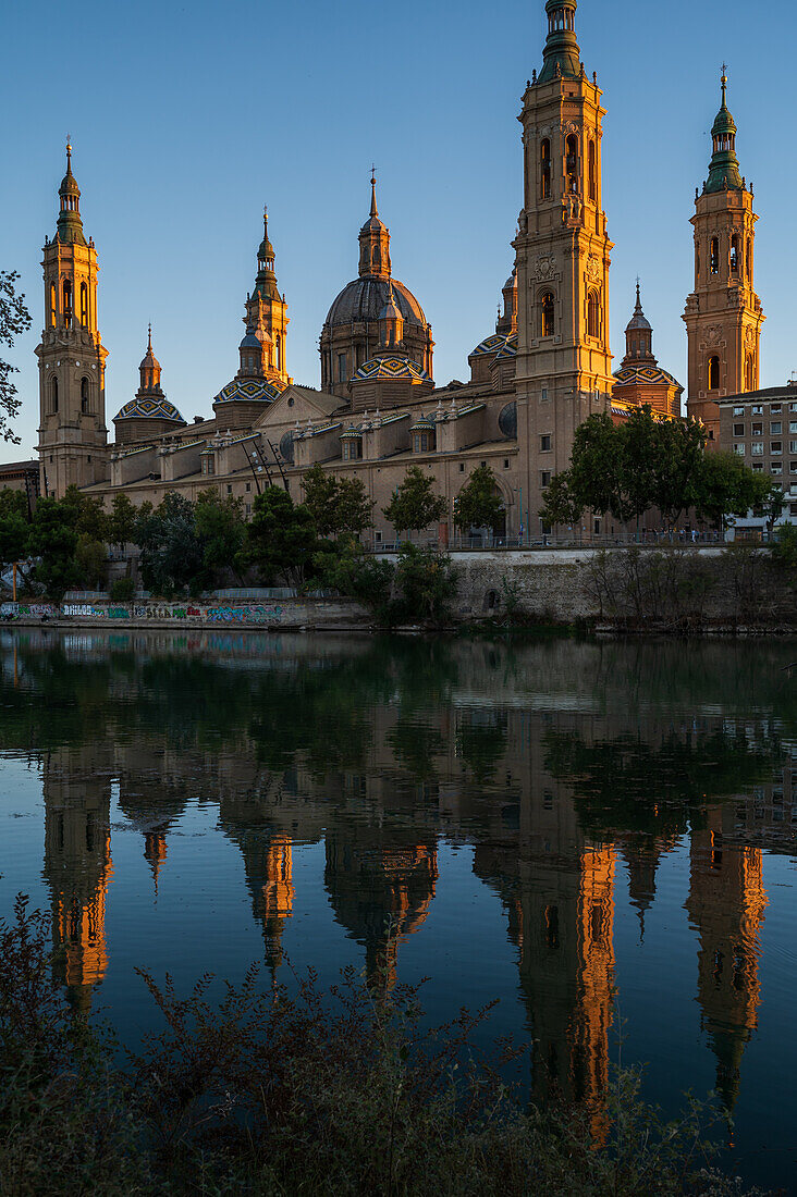 Cathedral-Basilica of Our Lady of the Pillar reflected on the Ebro River at sunset, Zaragoza, Spain