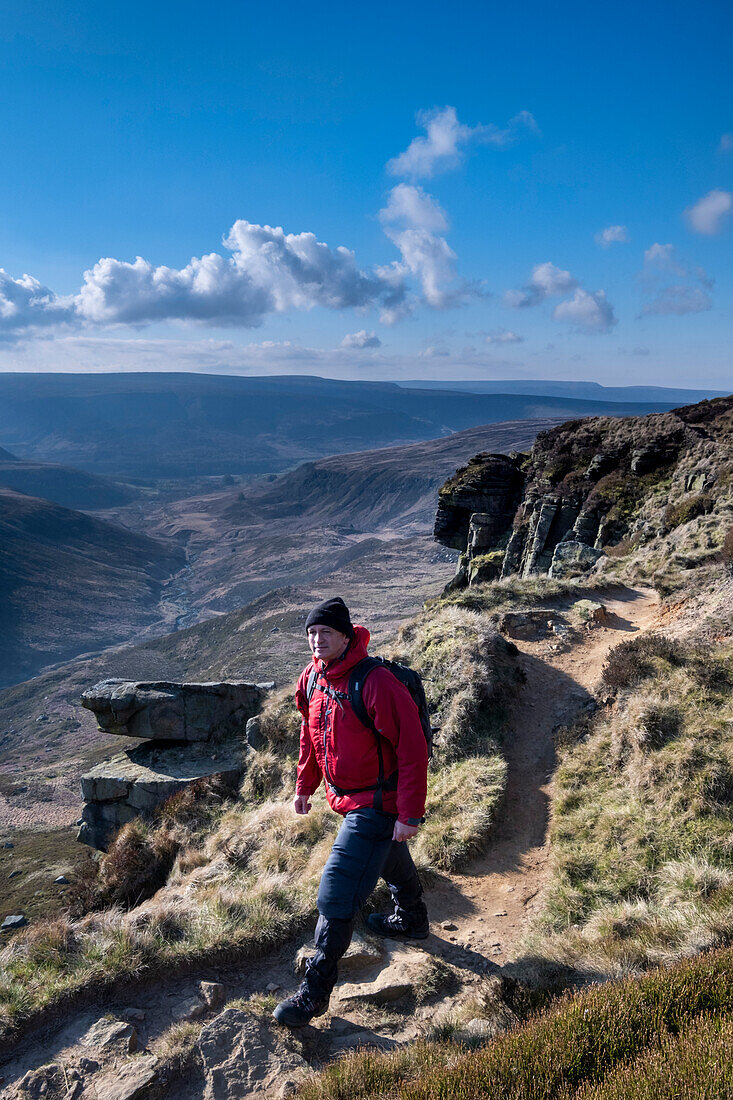 Walker on the Pennine Way at Laddow Rocks backed by Crowden Great Brook valley, Peak District National Park, Derbyshire, England, United Kingdom, Europe