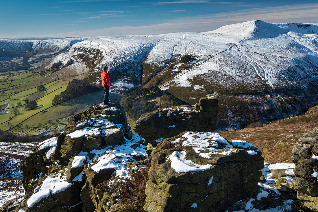 Walker looks out over Grindslow Knoll and the Edale Valley from Ringing Roger rock formation in winter, Kinder Scout, Peak District National Park, Derbyshire, England, United Kingdom, Europe