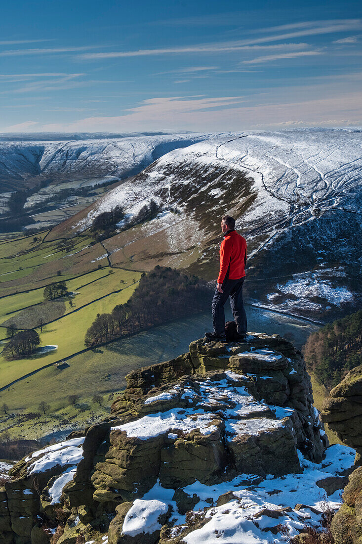 Wanderer blickt im Winter von der Felsformation Ringing Roger auf das Edale Valley, Kinder Scout, Peak District National Park, Derbyshire, England, Vereinigtes Königreich, Europa