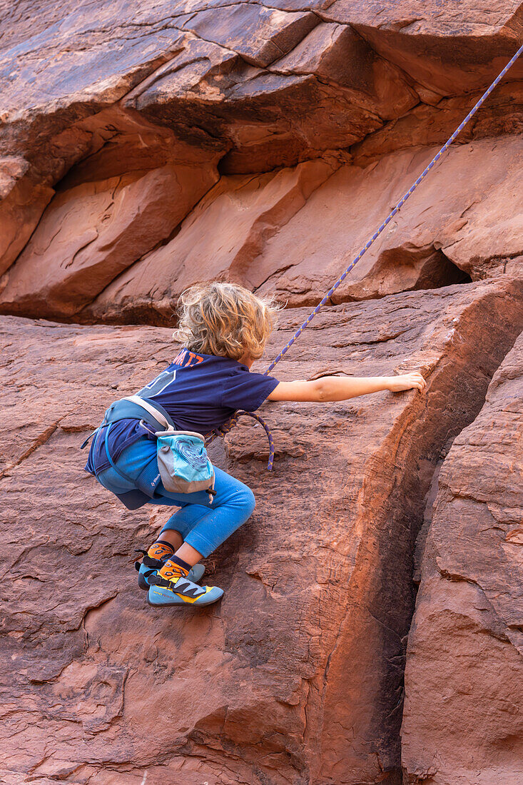 Ein 6-jähriger Junge lernt im Hunter Canyon in der Nähe von Moab, Utah, das Klettern.