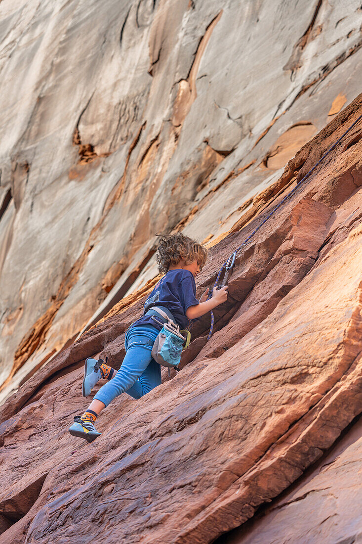 Ein 6-jähriger Junge lernt im Hunter Canyon in der Nähe von Moab, Utah, das Klettern.