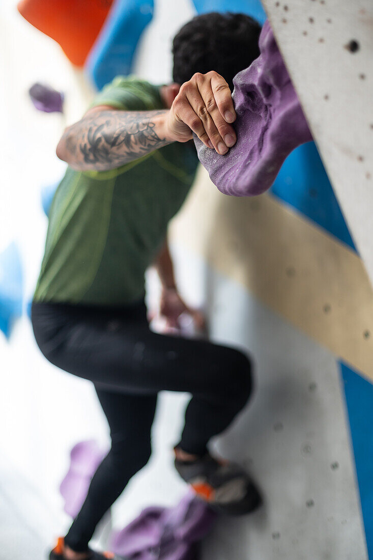 Young man in his twenties climbing on a climbing wall indoors