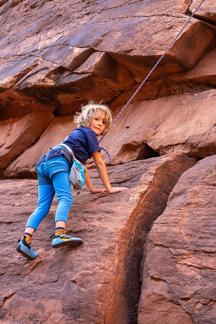 Ein 6-jähriger Junge lernt im Hunter Canyon in der Nähe von Moab, Utah, das Klettern.