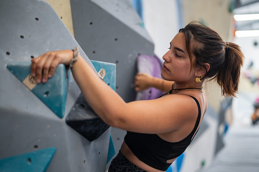 Young man in her twenties climbing on a climbing wall indoors