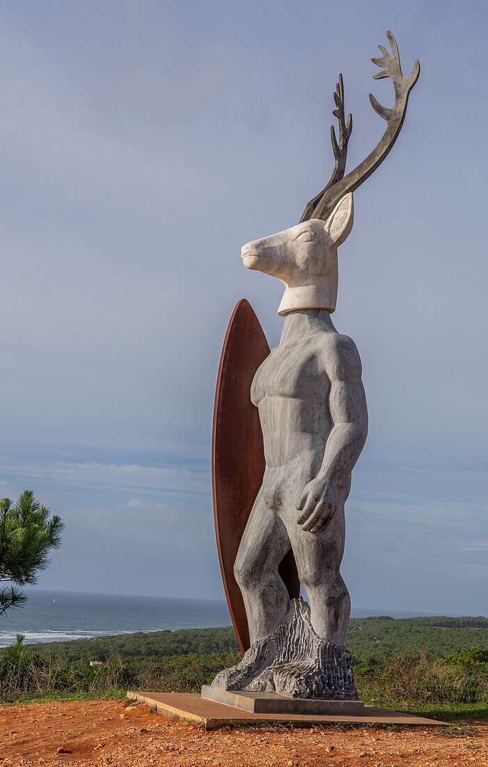 Statue eines Surfers am windigen Nordstrand von Nazare, dem Austragungsort eines der größten Surfwettbewerbe der Welt mit 30 m hohen Wellen, Nazare, Portugal, Europa