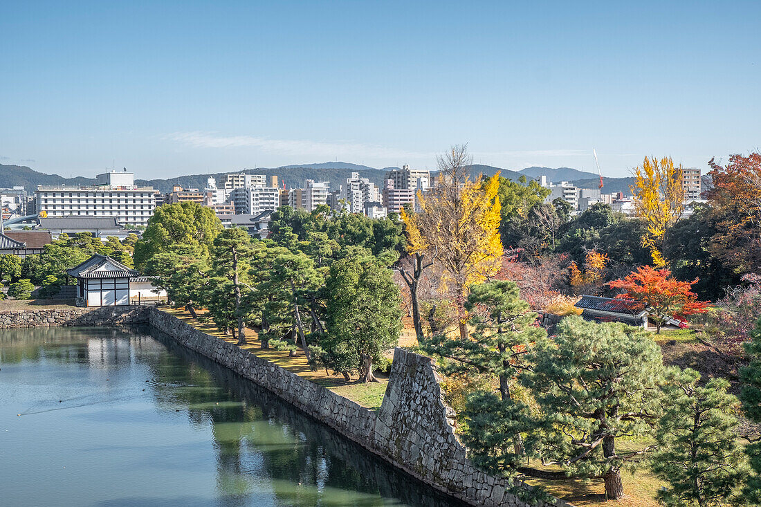 Nijo Castle garden and moat in autumn with the modern city in the background, Kyoto, Honshu, Japan, Asia