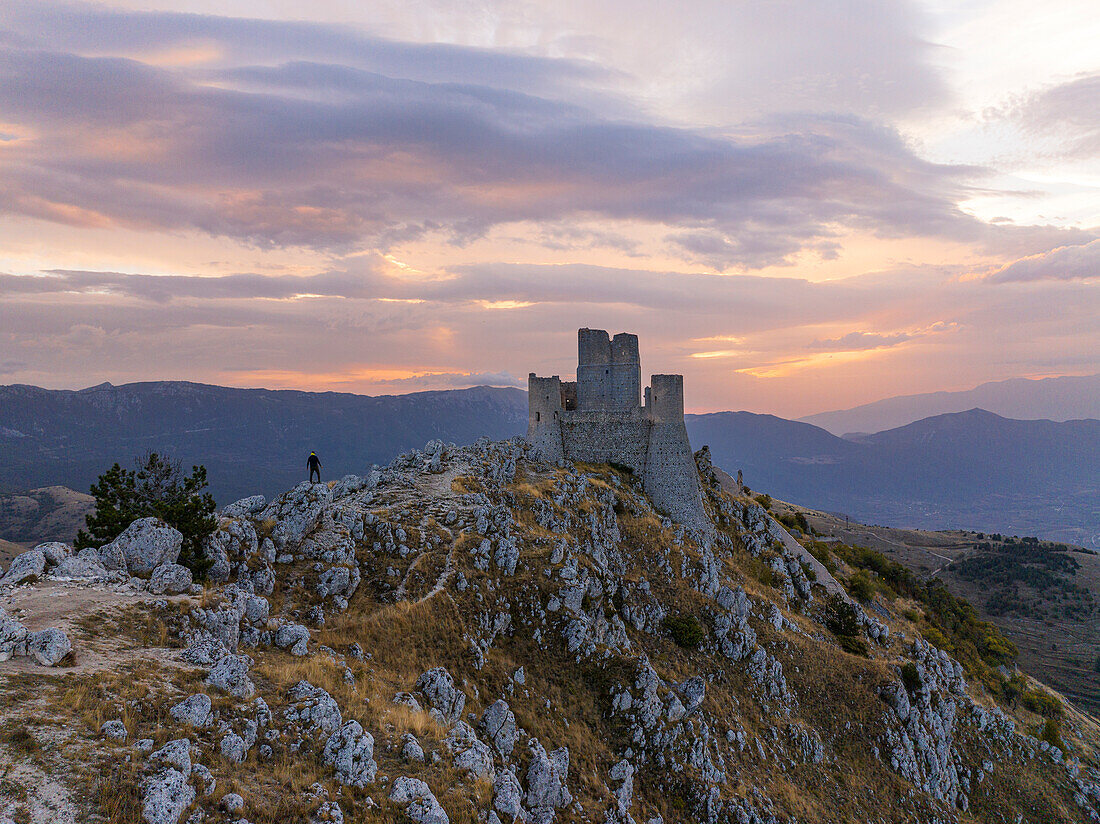 A person admires the Rocca Calascio castle during an autumn sunrise, National Park of Gran Sasso and Monti of Laga, Abruzzo, Italy, Europe