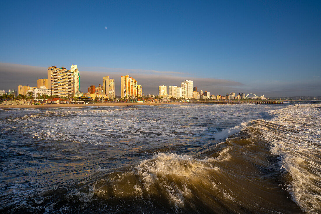 Blick auf Strandpromenade, Strand und Hotels vom Pier im Indischen Ozean bei Sonnenaufgang, Durban, Provinz KwaZulu-Natal, Südafrika, Afrika