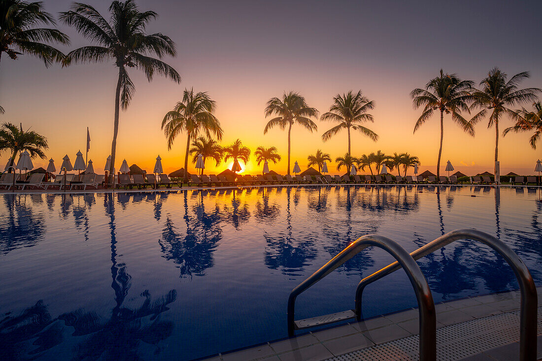 Blick auf Sonnenaufgang und Palmenreflexionen im Hotelpool bei Puerto Morelos, Karibikküste, Yucatan-Halbinsel, Mexiko, Nordamerika