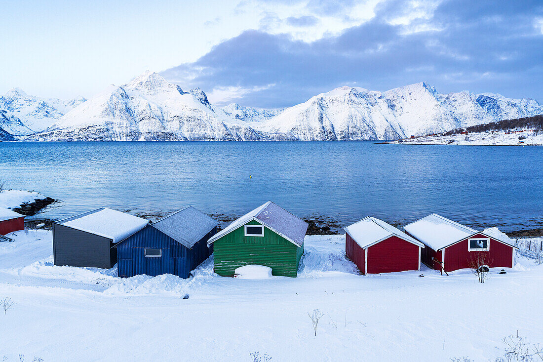 Bunte Holzrorbu mit Schnee bedeckt in der eisigen Landschaft am Fjord, Djupvik, Olderdalen, Lyngenfjord, Lyngen Alpen, Troms og Finnmark, Norwegen, Skandinavien, Europa