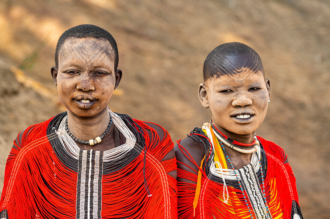 Mundari-Frauen in traditionellen Kleidern mit Narben und Asche im Gesicht, posieren auf einem Felsen, Stamm der Mundari, Südsudan, Afrika