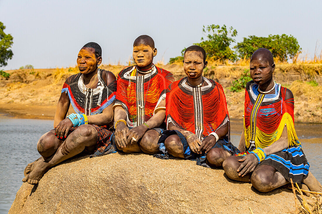 Mundari-Frauen in traditionellen Kleidern, mit Narben im Gesicht und Asche im Gesicht, posieren auf einem Felsen, Mundari-Stamm, Südsudan, Afrika