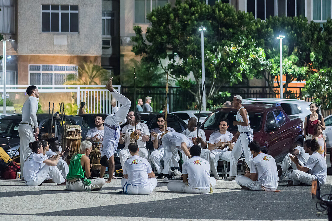 Menschen üben Capoeira, eine schnelle und vielseitige Kampfsportart, die in der Kolonialzeit auf den Kampf zwischen Sklaven und ihren Herren in Unterzahl oder bei technischem Nachteil ausgerichtet war, Copacabana, Rio de Janeiro, Brasilien, Südamerika