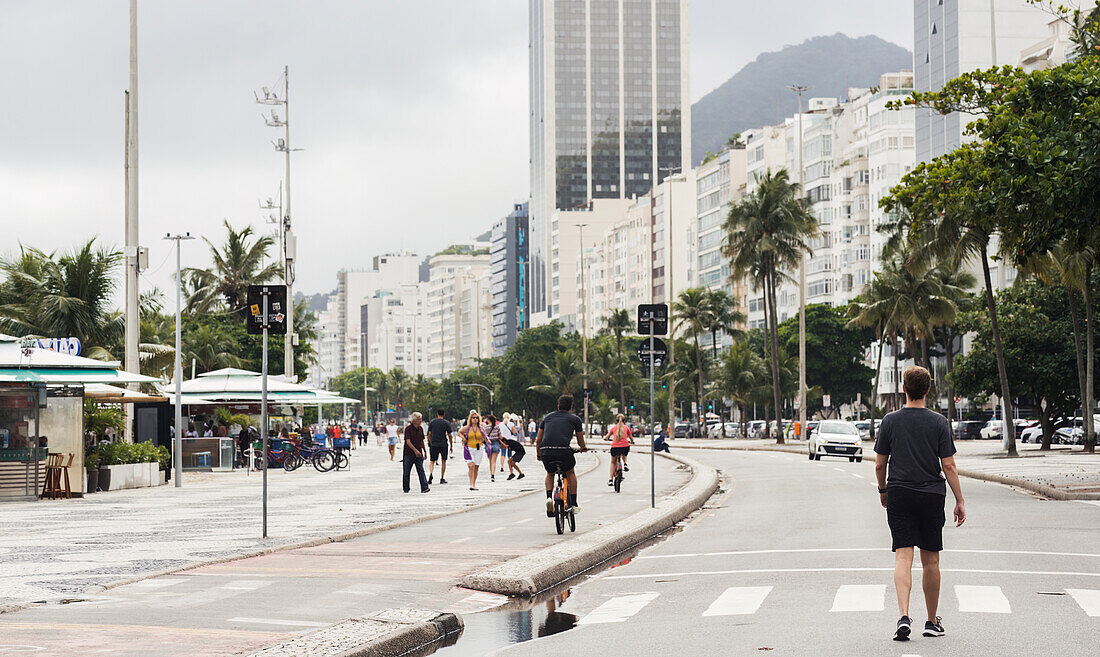 Junger Mann geht auf der Straße neben der Strandpromenade am Copacabana Beach, Rio de Janeiro, Brasilien, Südamerika