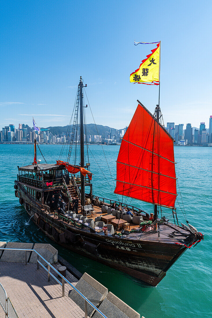 Traditionelles Segelboot mit rotem Segel und Hochhäusern in der Ferne, Central Hongkong, China, Asien