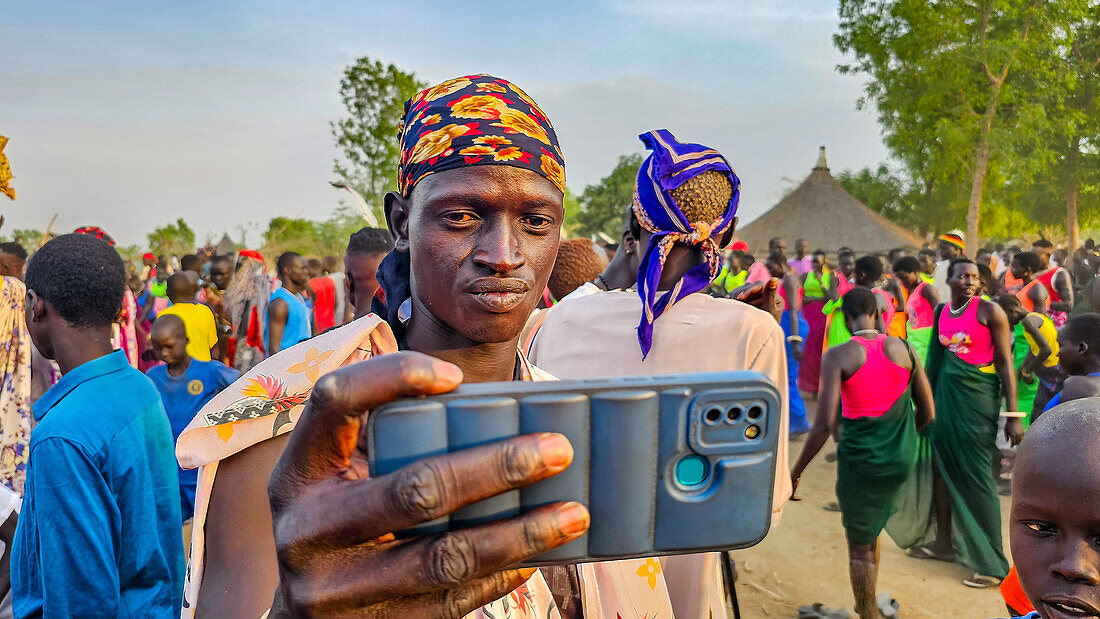 Man with cellphone taking a photo at a traditional Dinka wedding, Bor, central region, South Sudan, Africa