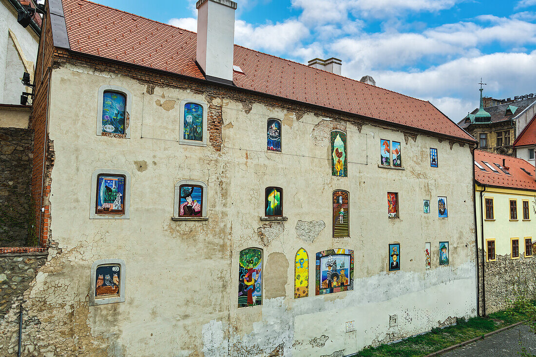 Lebhaftes Graffiti an den Fenstern und der Wand eines alten Hauses mit Dachziegeln, Bratislava, Slowakei, Europa