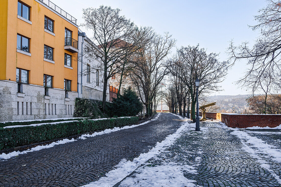 Budaer Burg mit Gebäuden neben einem Kopfsteinpflasterweg im Winter mit schmelzendem Schnee drum herum, Budapest, Ungarn, Europa