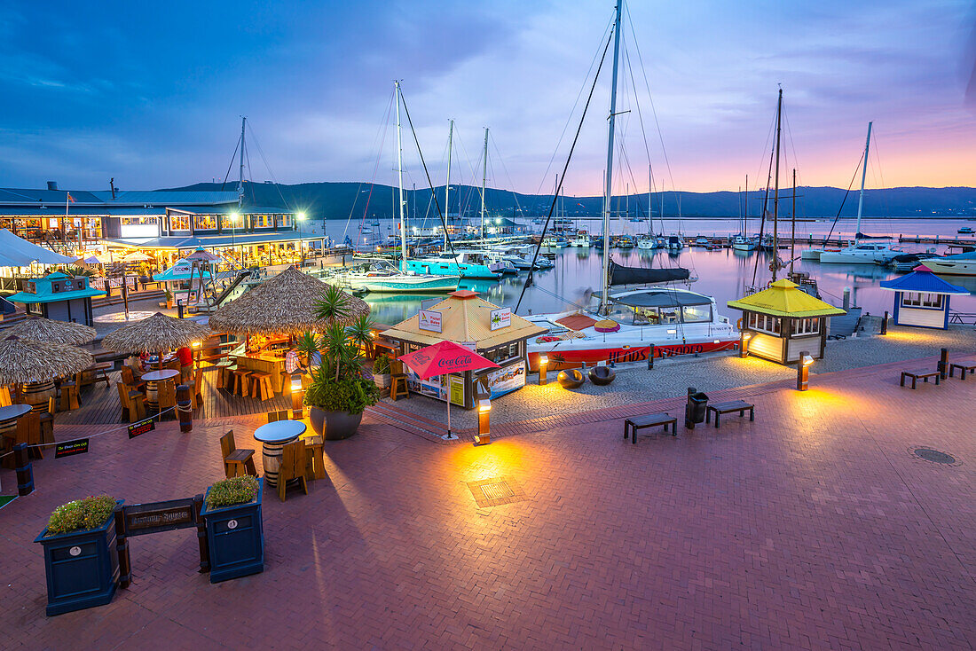 Blick auf Boote und Restaurants an der Knysna Waterfront in der Abenddämmerung, Knysna, Westkap, Südafrika, Afrika