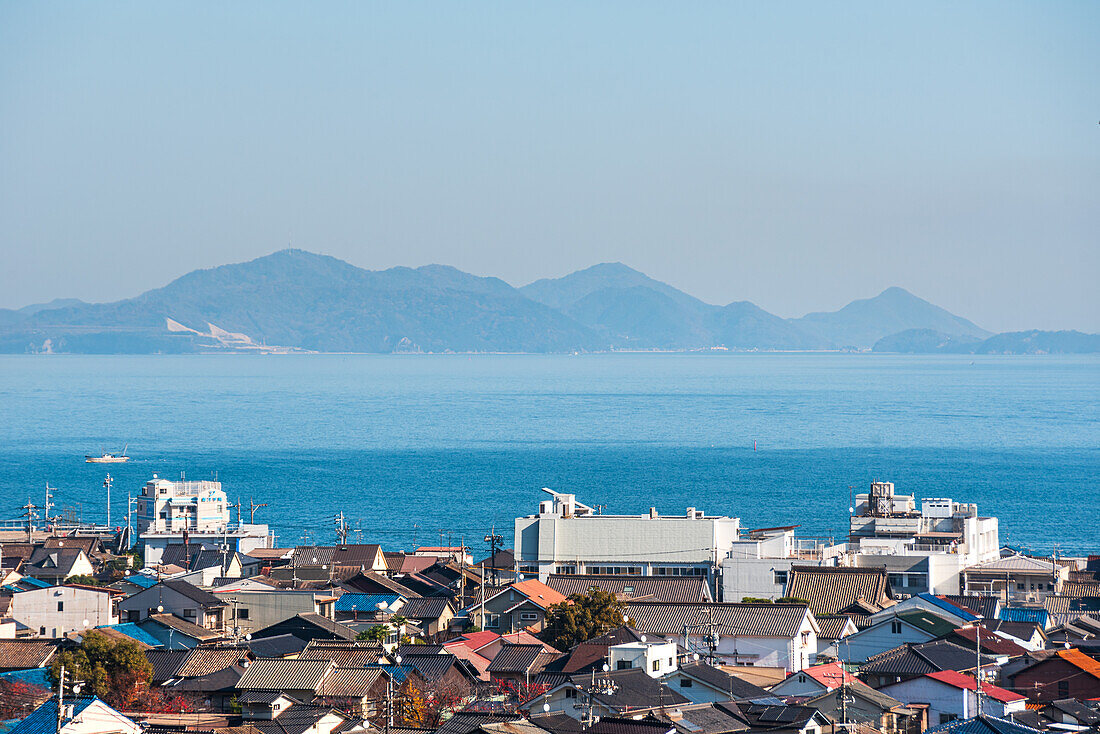 Dächer der Küstenstadt, ruhiges blaues Meer und Inseln am Horizont, Tomonoura, Honshu, Japan, Asien