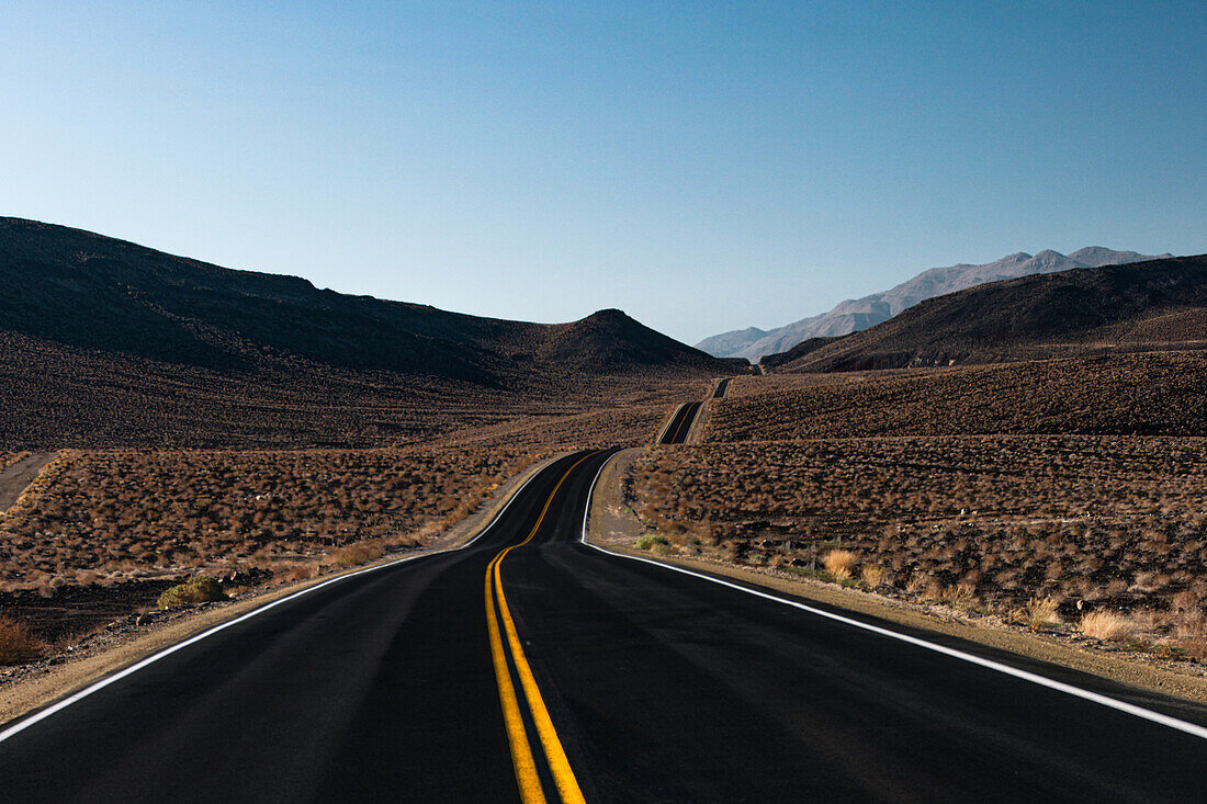 Einsamer hügeliger Highway in der Wüste von Death Valley, Kalifornien, Vereinigte Staaten von Amerika, Nordamerika