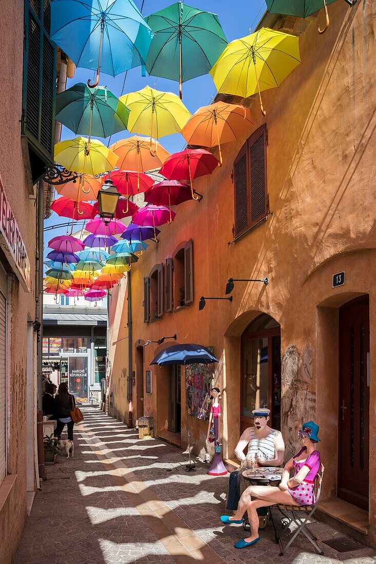 France, Var, Saint-Raphaël, Arts district, papier-mâché sculpture by artist Liliana Anic and multicolored umbrellas hanging over rue du Safranier