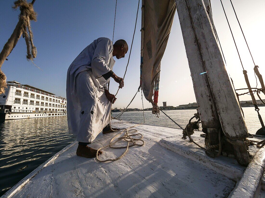 Ägypten, Oberägypten, Nubien, Niltal, Assuan, An Bord einer Feluke faltet der Kapitän sein Segel vor dem Anlegen