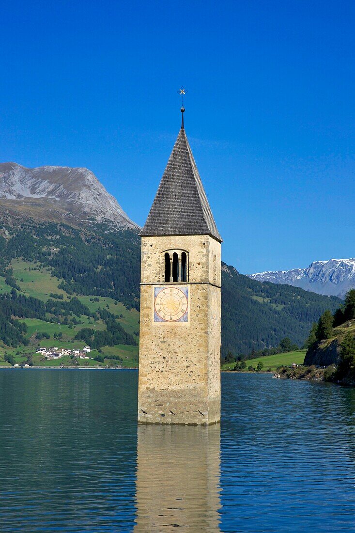 Italien, autonome Provinz Bozen, Reschensee, verschlungener Kirchturm, der aus dem Wasser des Sees auftaucht, umgeben von üppig bewachsenen Bergen