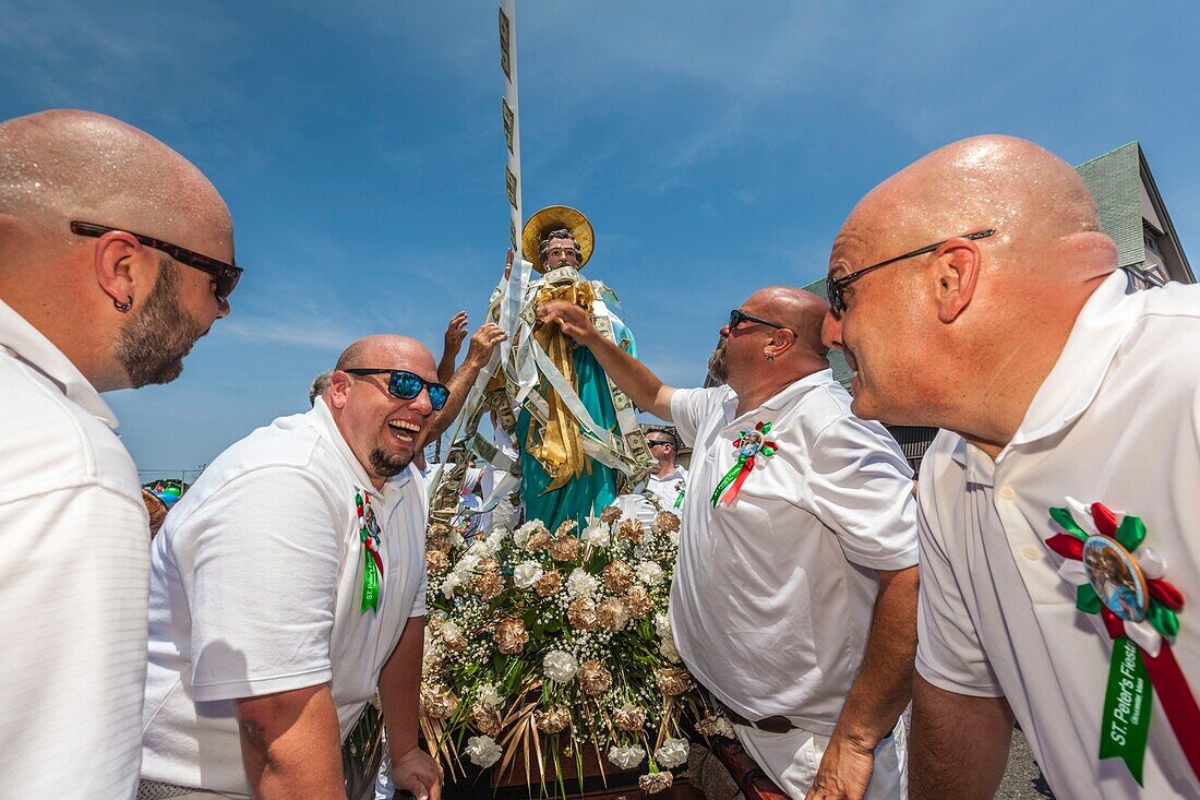 United States, New England, Massachusetts, Cape Ann, Gloucester, Saint Peters Fiesta, Traditional Italian Fishing Community Festival, men attaching ropes of money donations to the statue of St. Peter