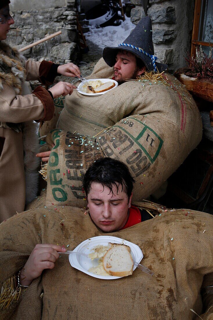 Schweiz, Kanton Wallis, Val d'Herens, Dorf Evolene, Karneval, Vorbereitung der Empailles (junge Männer, die mit alten Säcken gekleidet sind, die mit ca. 50 kg Stroh gestopft sind) und eine lokal geschnitzte Holzmaske tragen, die mythische und oft furchterregende Tiere darstellt