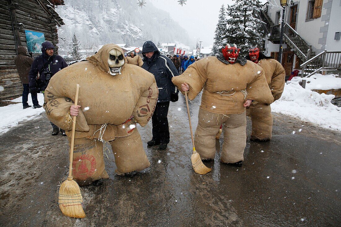 Schweiz, Kanton Wallis, Val d'Herens, Dorf Evolene, Karneval, Vorbereitung der Empailles (junge Männer, die mit alten Säcken gekleidet sind, die mit ca. 50 kg Stroh gestopft sind) und eine lokal geschnitzte Holzmaske tragen, die mythische und oft furchterregende Tiere darstellt