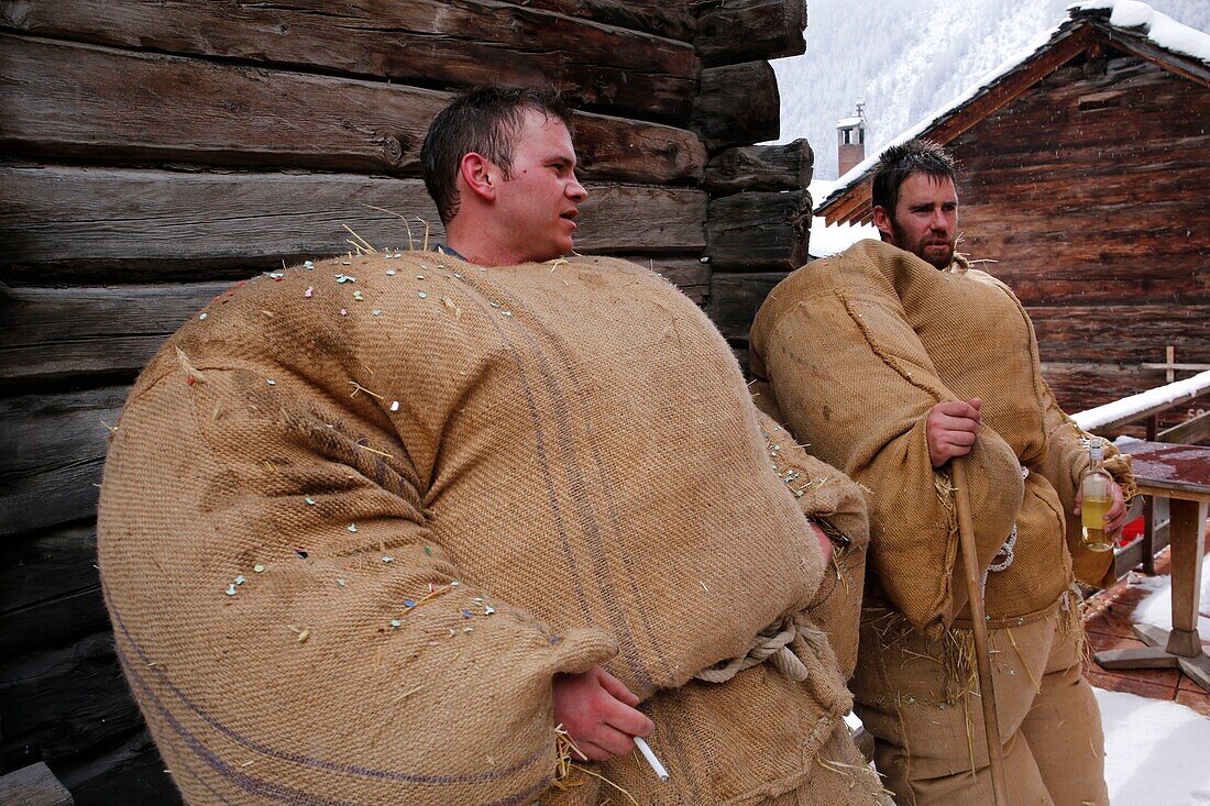 Schweiz, Kanton Wallis, Val d'Herens, Dorf Evolene, Karneval, Vorbereitung der Empailles (junge Männer, die mit alten Säcken gekleidet sind, die mit ca. 50 kg Stroh gestopft sind) und eine lokal geschnitzte Holzmaske tragen, die mythische und oft furchterregende Tiere darstellt