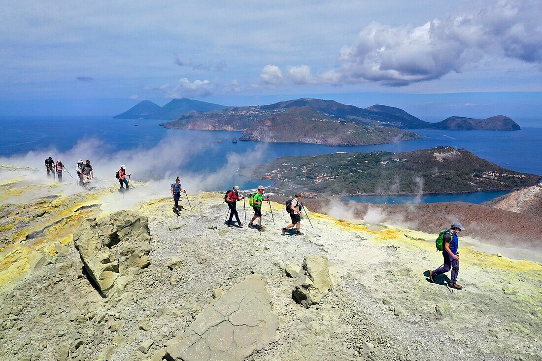 Italien, Sizilien, Äolische Inseln, Weltnaturerbe der UNESCO, Insel Vulcano, Wanderer am Kraterrand des Vulkans della Fossa durch Schwefelfumarolen, im Hintergrund die Insel Lipari und die Insel Salina (Luftaufnahme)