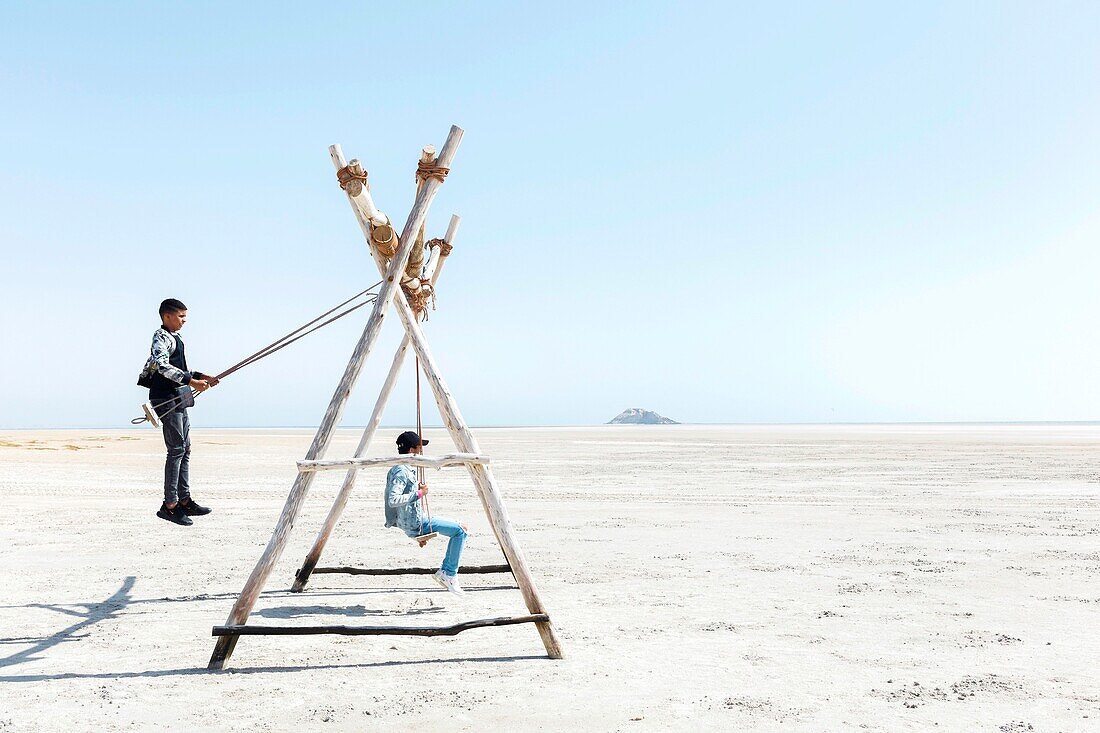 Marocco, Oued Ed-Dahab, Dakhla, Dakhla Attitude Resort, teens on swings on a beach at low tide