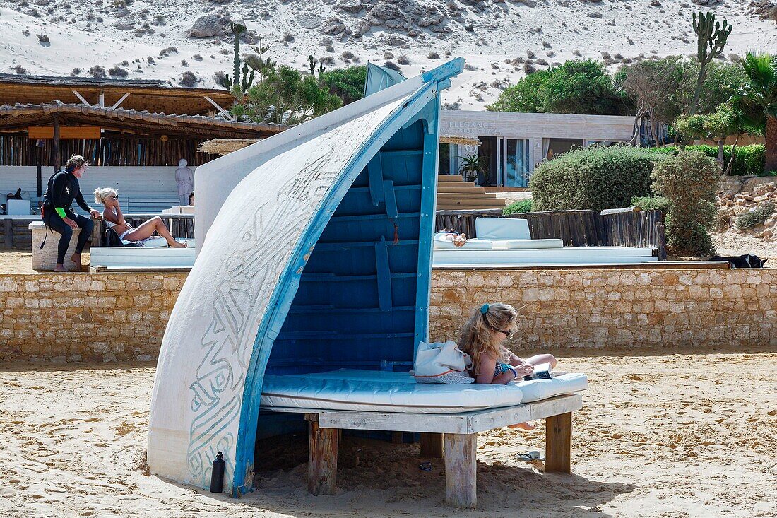 Marokko, Oued Ed-Dahab, Dakhla, Ocean Vagabond Resort, Gäste einer luxuriösen Öko-Lodge sitzen auf einer Strandliege in der Sonne