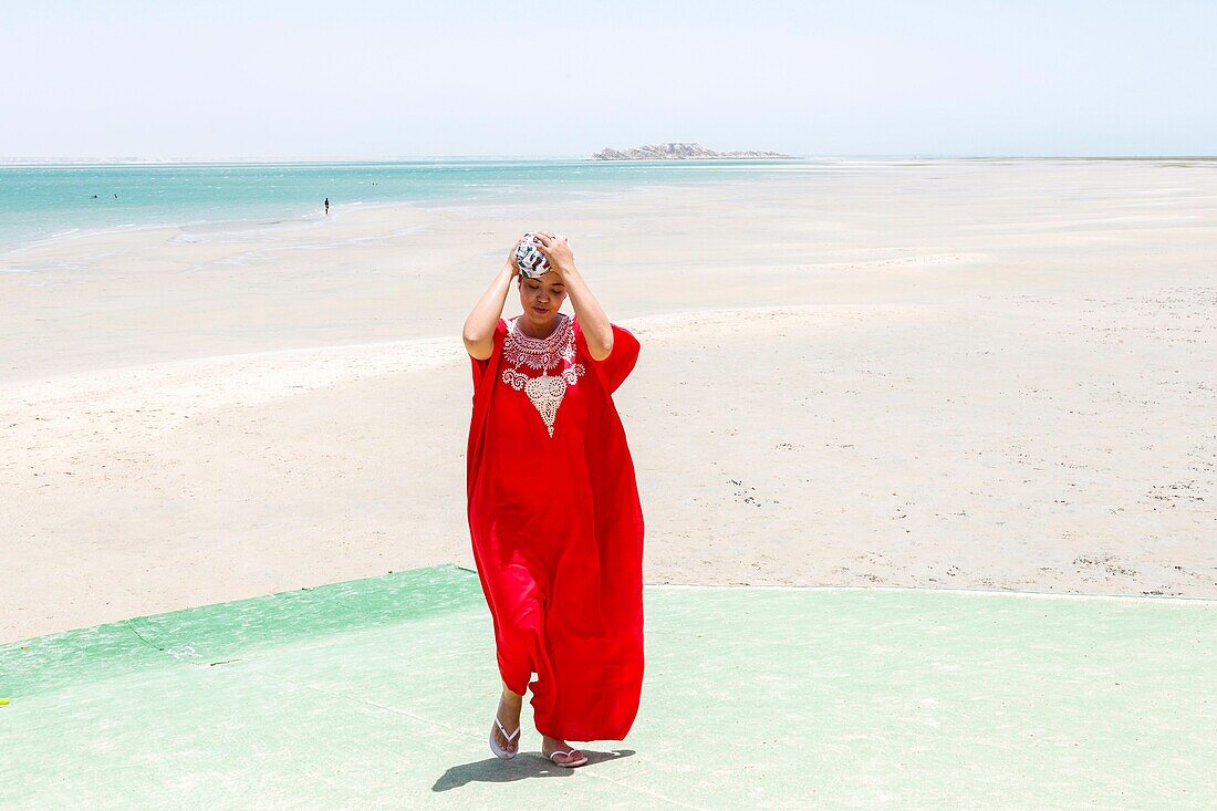 Marokko, Oued Ed-Dahab, Dakhla, PK25 Resort, junge marokkanische Frau in traditioneller Kleidung am Strand bei Ebbe