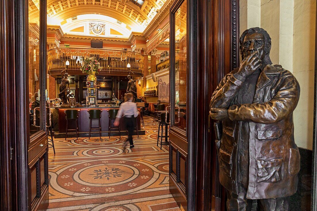 Irland, Dublin, Green College, Bar und Restaurant The Bank, untergebracht in der Lobby einer ehemaligen Bank, viktorianische Architektur, am Eingang die Statue von Con Houlihan, einem der berühmtesten Sportjournalisten Irlands