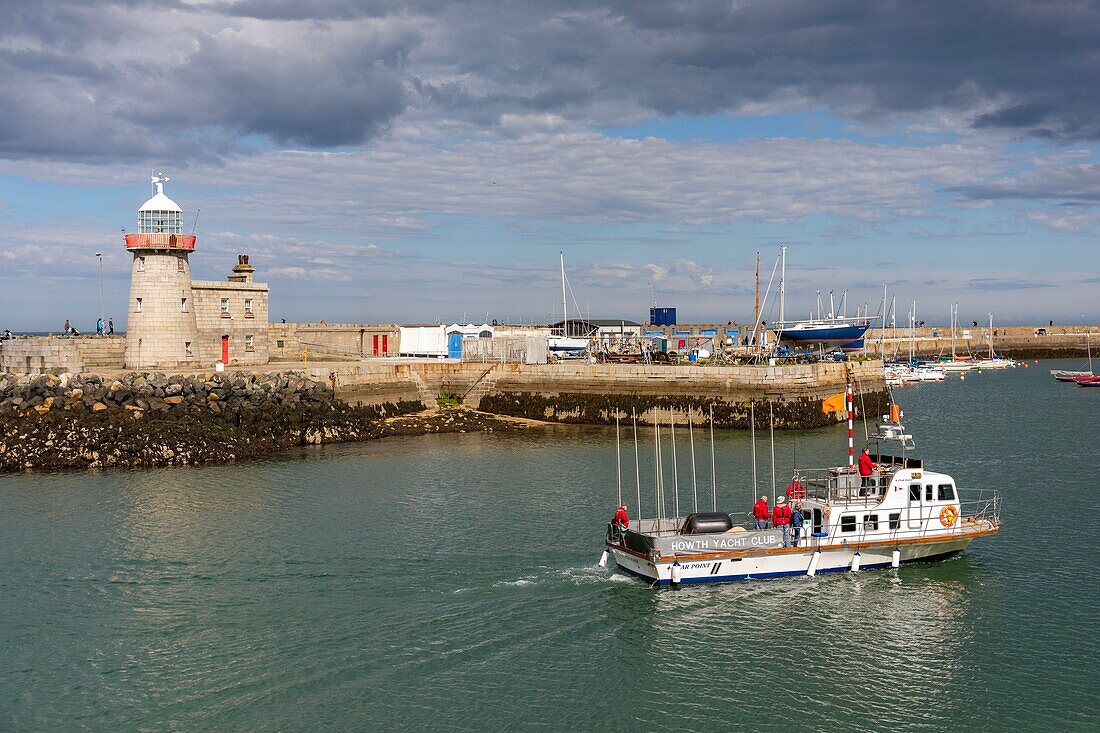 Ireland, Fingal County, northern suburbs of Dublin, Howth, the return of a sport fishing boat to the harbor, passing in front of the lighthouse of the city