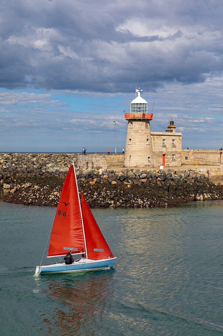 Ireland, Fingal County, northern suburbs of Dublin, Howth, the return of a sailboat to port, passing in front of the lighthouse of the city