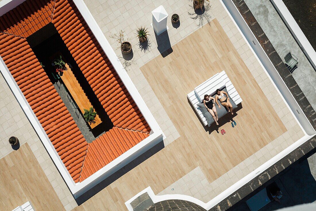 Spain, Canary Islands, La Palma, tourists resting at the edge of a swimming pool located by the sea (aerial view)