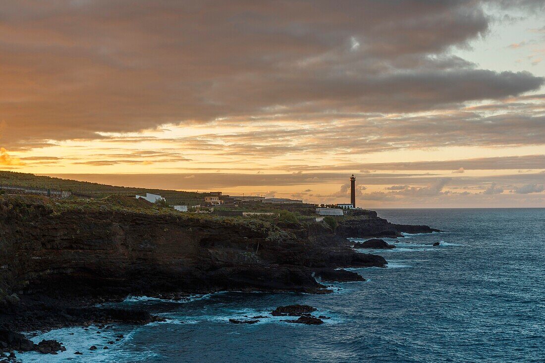 Spain, Canary Islands, La Palma, view of a lighthouse against the light by the sea at sunset